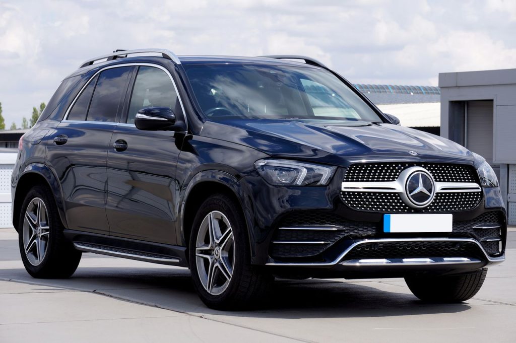 A sleek black Mercedes-Benz SUV parked on a city pavement under a cloudy sky in Lincoln, UK.